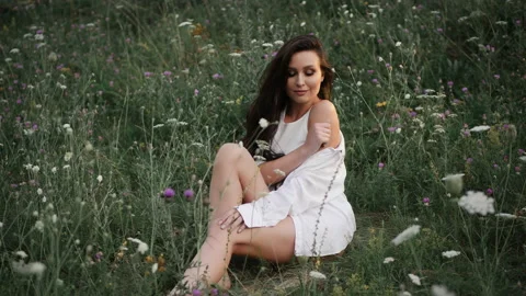Girl posing at camera while sitting on the grass in the meadow Stock Footage 136507221