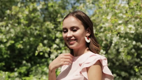 Girl posing in front of a blooming garden, flowering Apple trees, summer, spring Stock Footage 108824701