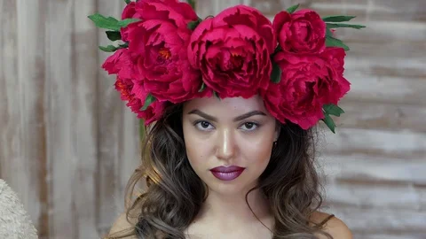Girl posing in front of camera. young woman in a wreath of scarlet peonies on Stock Footage 88057099