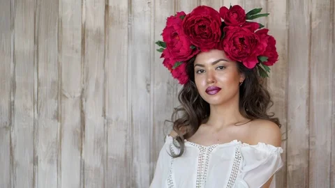 Girl posing in front of camera. young woman in a wreath of scarlet peonies on Stock Footage 88149610