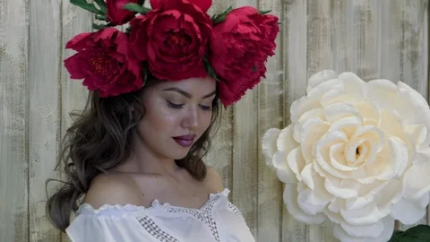 Girl posing in front of camera. young woman in a wreath of scarlet peonies on Stock Footage 88150227