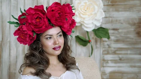 Girl posing in front of camera. young woman in a wreath of scarlet peonies on Stock Footage 88408965