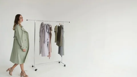 Girl posing in a gray unbuttoned cloak and spinning next to the clothes rack  Stock Footage 108178226