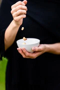 Girl pouring hazelnuts into a white cup Stock Photos