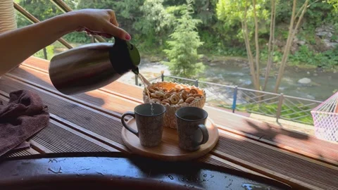 A girl pours tea into cups while sitting in a vat against the backdrop of a Stock Footage 251746951