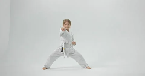 The girl practices karate at home. The child is dressed in a kimono on a white Stock Footage