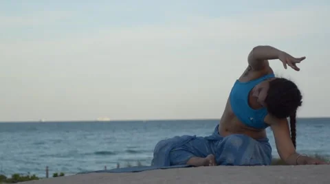 Girl practicing lateral stretching for flexibility outdoors on the blue tropical 스톡 동영상 63324465