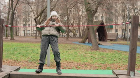 Girl practicing on playground rope. Young girl balancing on playground rope in Stock Footage 337372629