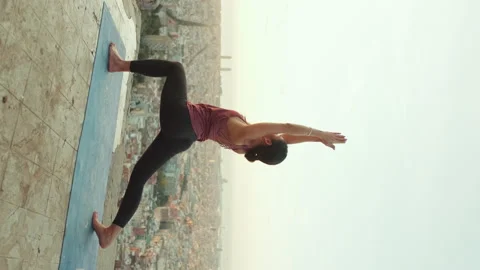 Girl practicing yoga warrior pose at lookout point at dawn Stock Footage 229503258