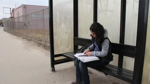 Girl prepares homework at bus stop Stock Footage 155488520