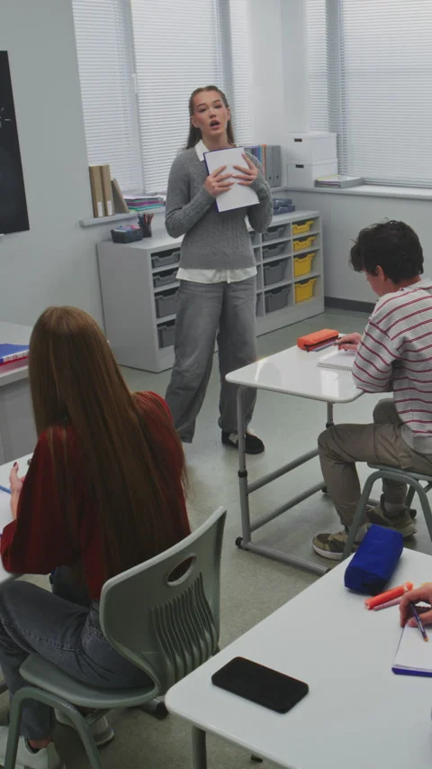 Girl Presents Project to Classmates While Teacher Observes With Interest Stock Footage 321003297