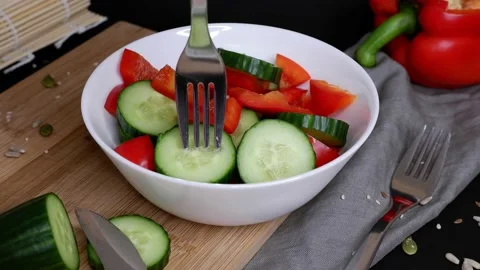The girl pricks a cucumber on a fork. Vegetable salad. Stock Footage 155247379
