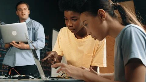 Girl programing or coding system while african boy fixing model. Edification. Foto stock
