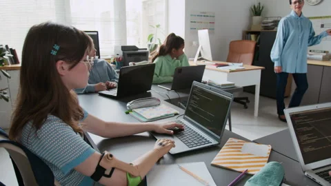 Girl with Prosthetic Arm Typing Code on Laptop During Group Programming Lesson Stock Footage 317640195