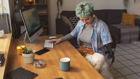 Girl with Prosthetic Arm Using Computer and Playing with Dog Video stock 244917736