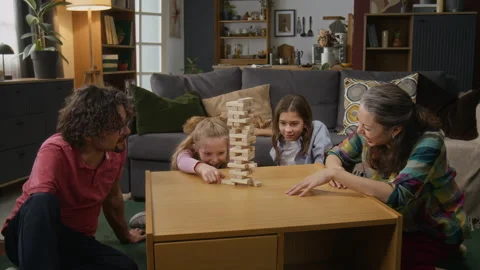 Girl Pulling out Block and Tower Collapsing while Playing with Family Stock Footage 307352557