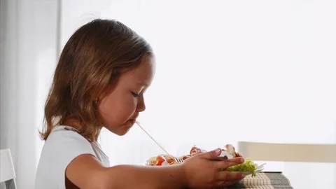 A girl is pulling pasta while eating at home, side view. Stock Footage 115249525