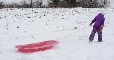 Girl pulling sled up the snow covered hill Stock Footage 70010285
