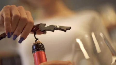 Girl pulls the cork from a wine bottle with a corkscrew close-up. A girl with a Stock Footage 99372906