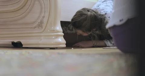 Girl pulls out a gray cat from under the bed Stock Footage 89115200