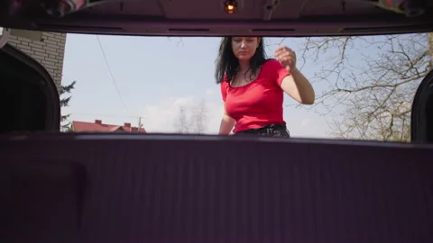 The girl pulls out a suitcase from the trunk of the car. Stock Footage 194778255