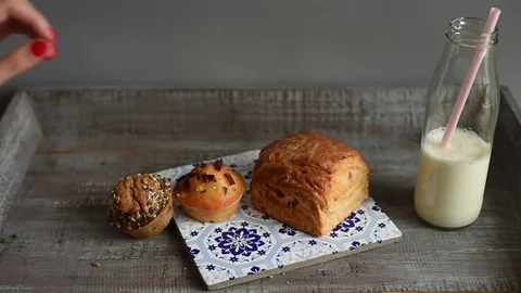 Girl puts bread and rolls on a plate with bottle of milk Stock-Footage 73233668