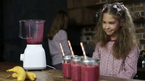 Girl puts drinking straws into jars with smoothie Stock Footage