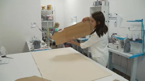 Girl puts a pattern for clothes on a cloth Stock Footage 135828715