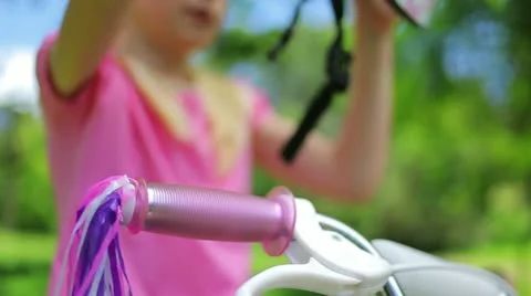 Girl puts on a pink cycling helmet and fastens the clasps Stock Footage