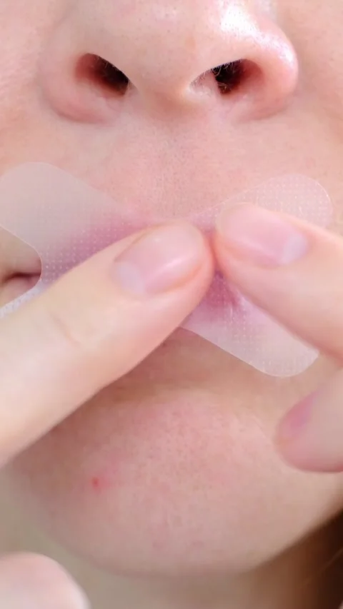 A girl puts a snoring patch on her mouth, close-up to sleep with her mouth Vídeos de archivo 317282115