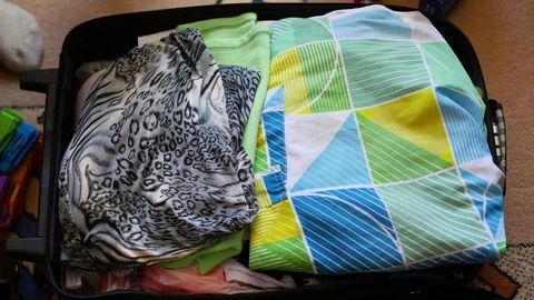 Girl puts things in the suitcase for travel in closeup Stock Footage
