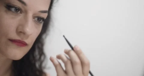 Girl putting on makeup in front of mirror. Lady applying make up. Close up .. Stock Footage 245493927
