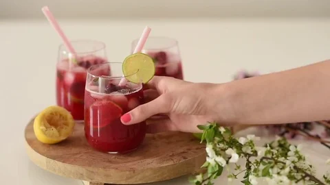 Girl putting slice of lime on corner of glass with raspberry cocktail and t.. Stock Footage 73741902