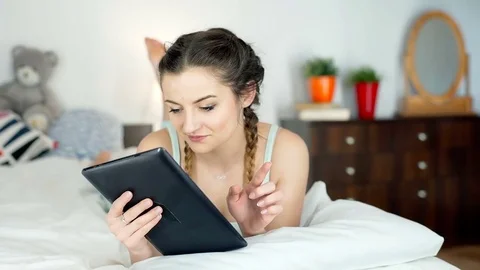 Girl in pyjamas browsing internet on tablet and smiling to the camera, steadycam Stock-Footage 72192933