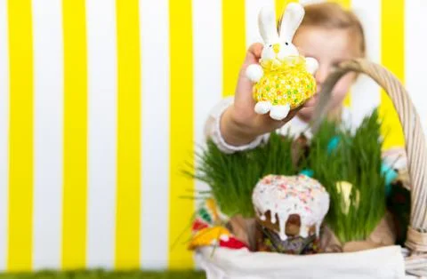 A girl with a rabbit on the backdrop of the Easter basket. Copy Space. Spring Stock Photos