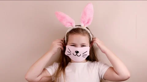 A girl with rabbit ears on her head is having fun, putting on a protective mask Stock Footage 147926041