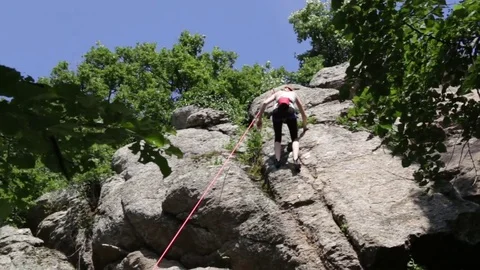Girl rappelling down a hill Stock Footage 80864589