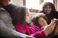 Girl Reading Book With Family In Bedroom Stock Photos