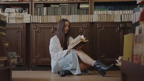 The girl is reading a book in the library Stock Footage 252039846