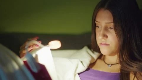 Girl reading a book at night with a reading lamp Stock Footage 346555083