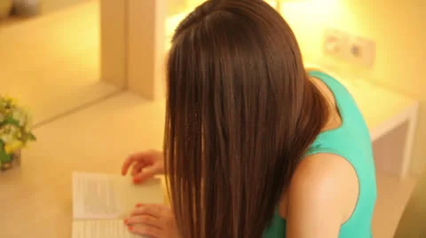 Girl reading a book at the table Stock Footage 23315593