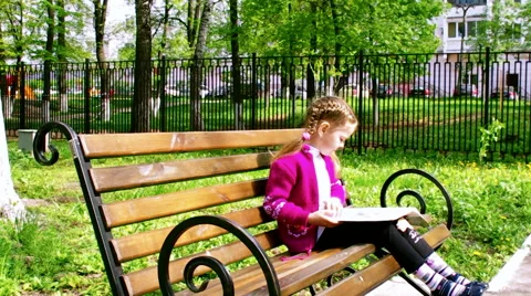 Girl reading a book while sitting on the bench Stock Footage 62925271