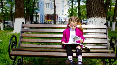Girl reading a book while sitting on the bench shooting slider Stock Footage 62925443
