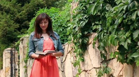 Girl reading a book while standing in the Park Stock Footage 67122450