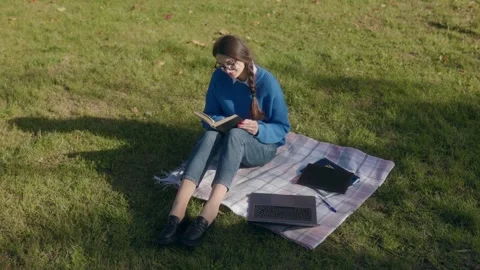 Girl reading a book while studying outdoors in autumn Video stock 300265524