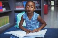 Girl Reading Braille Book In Library Stock Photos