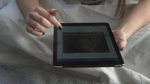 Girl reading on digital tablet lying in bed Stock Footage 71756773