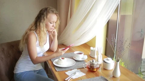 Girl reading text message on her phone while sitting in modern coffee shop Stock Footage 65877905