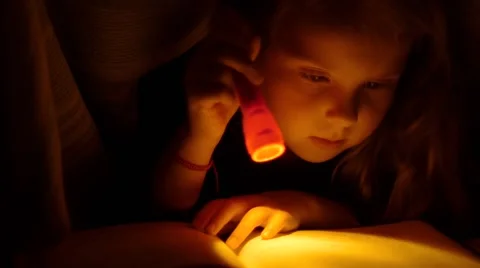 Girl reading under the covers with flashlight. Close Up Video stock 68619864