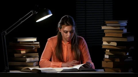 Girl reads and writes information in a notebook. Black background Stock Footage